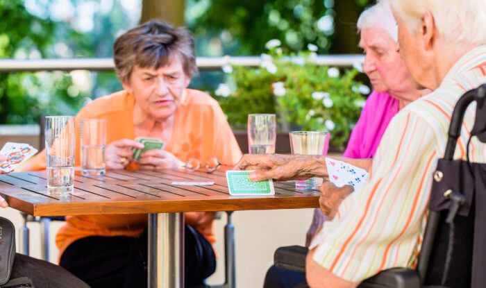 An elderly woman and her friends play cards