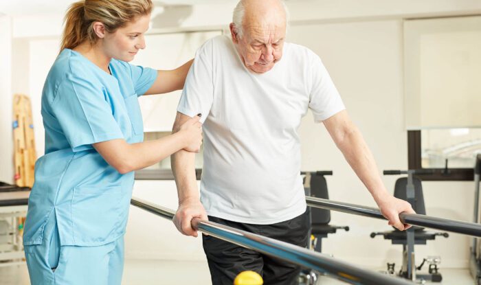 an elderly man has a caretaker help him with physical therapy