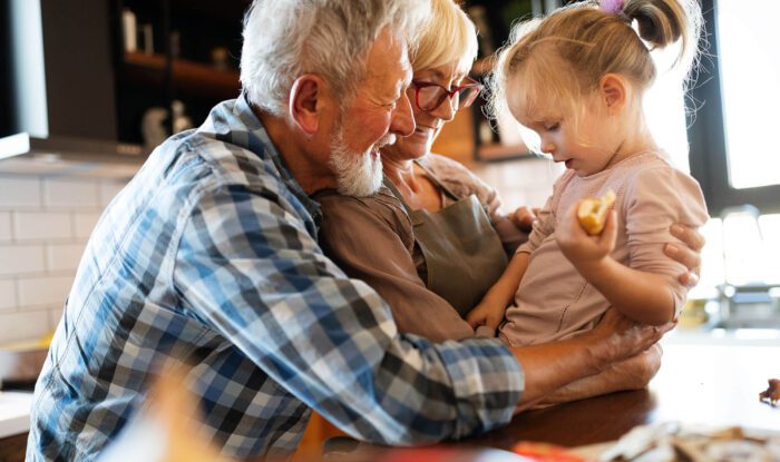 a grandpa and grandma hold their grandchild for a special occasion