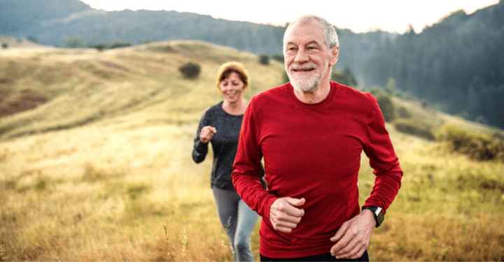 An elderly man jogs up a hillside with his wife behind him