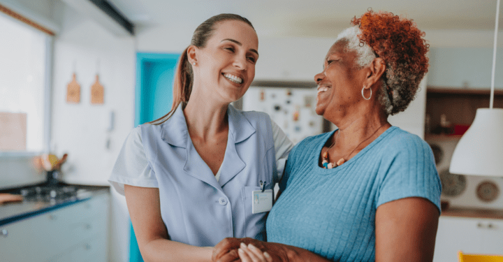 An elderly woman smiles at her post acute care nurse