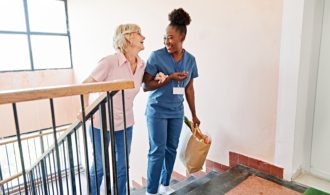 A Generations nurse helps an elderly woman up the stairs