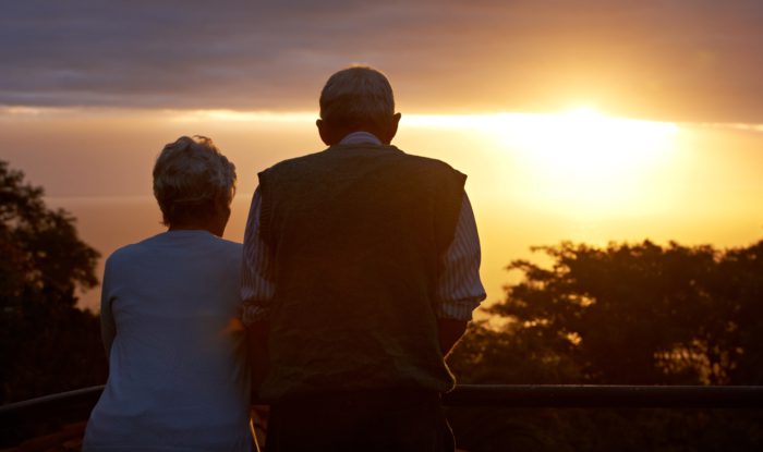 An older couple looks at a sunset