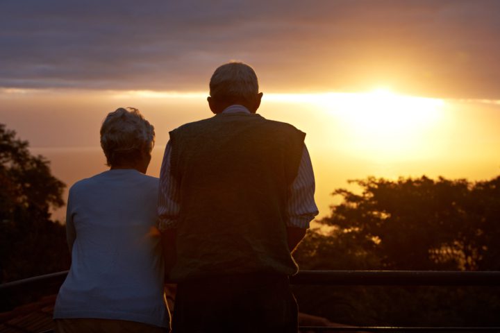 An older couple looks at a sunset